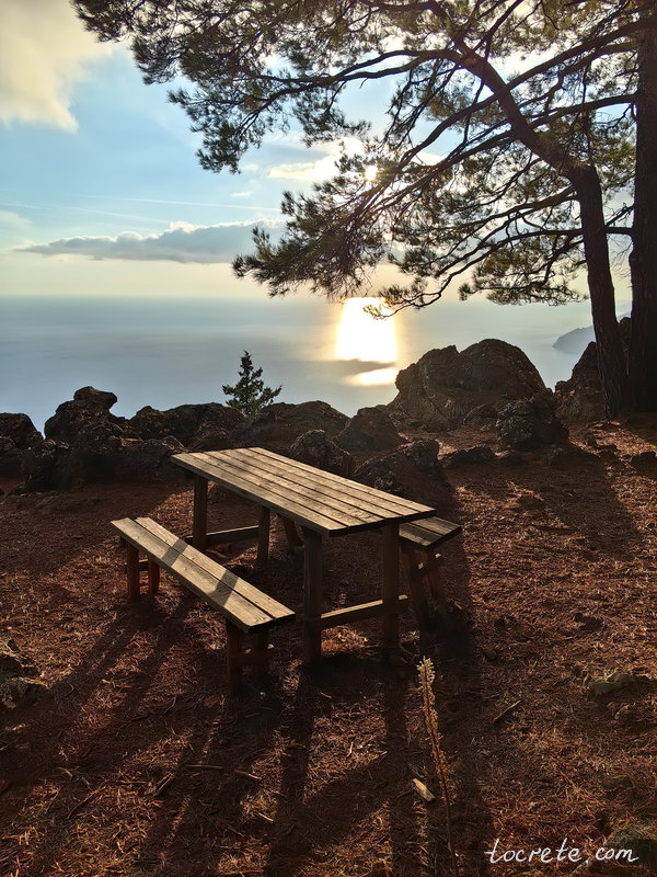 На балконе Агиос Яннис в тени деревьев установлен стол и лавки с видом на морскую даль На балконе Агиос Яннис в тени деревьев установлен стол и лавки с видом на морскую даль